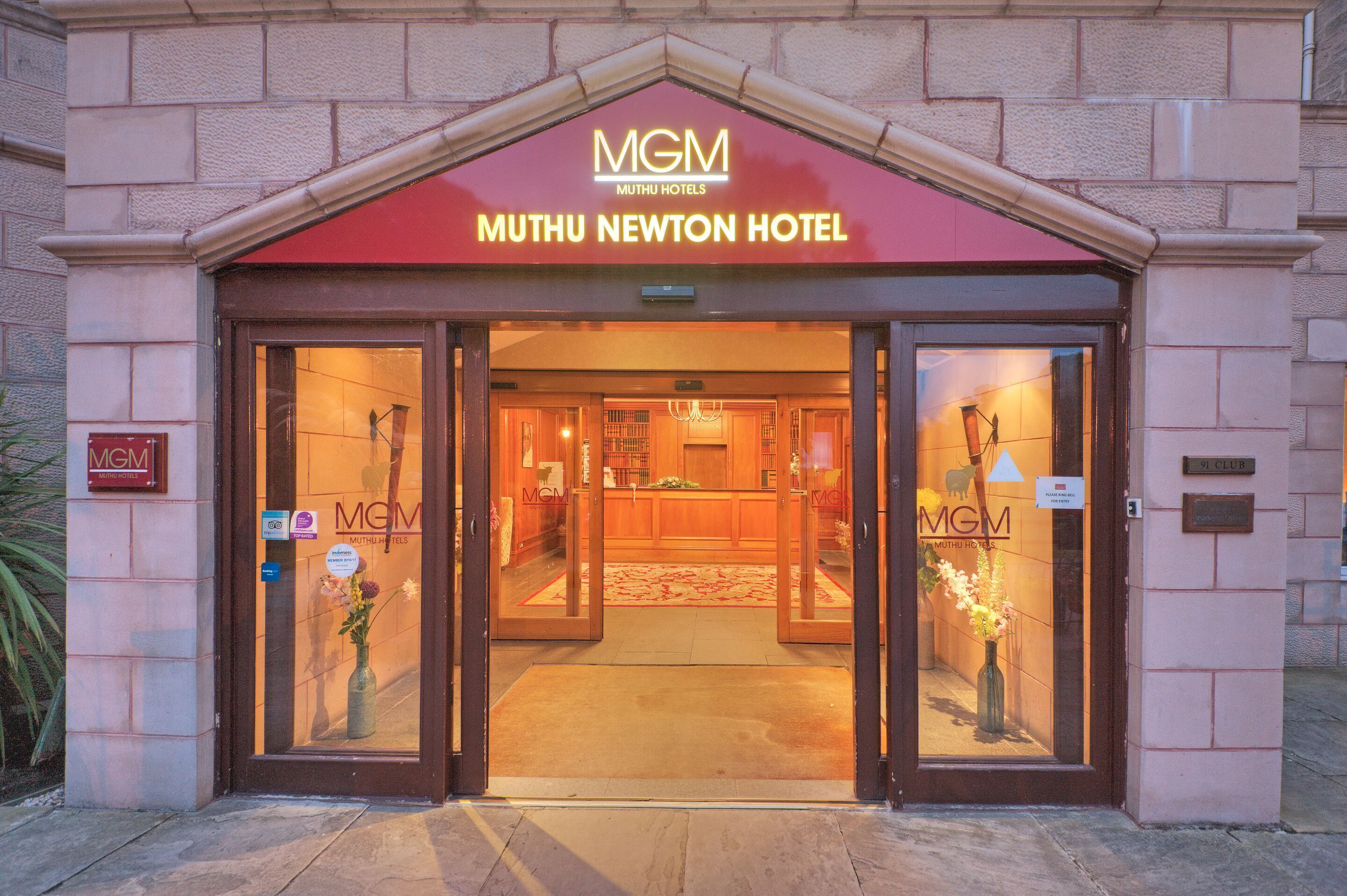Der Eingang zum MGM Muthu Newton Hotel mit rotem Vordach und Glastüren.