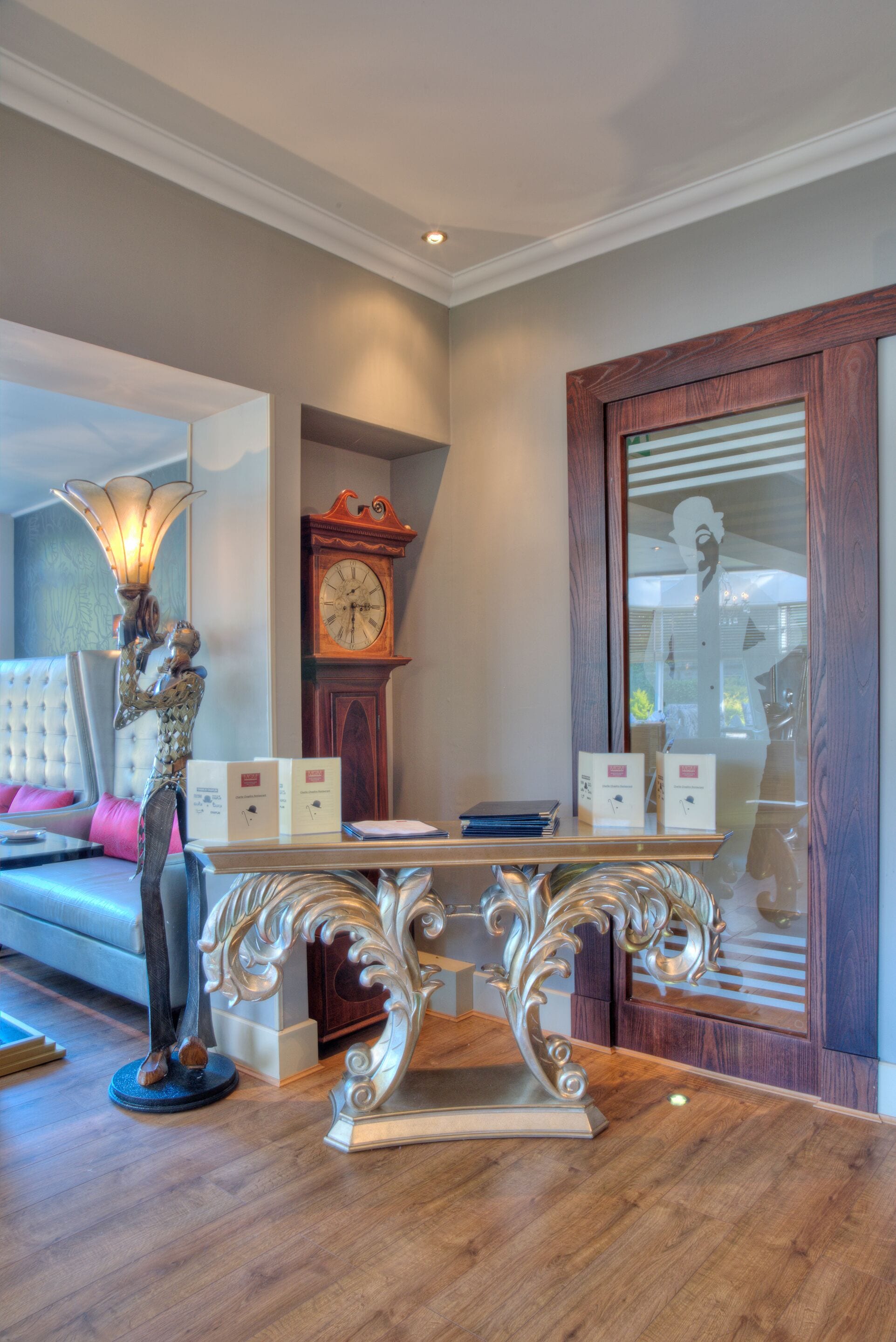 A living room with a sofa, a table with decorative items, a clock, and a large mirror.