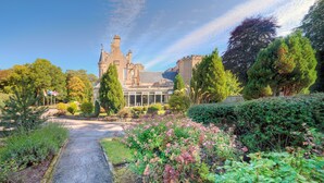 A historic building with a prominent tower, surrounded by lush gardens and a gravel pathway. - Muthu Newton Hotel (Near Inverness Airport) (Nairn)