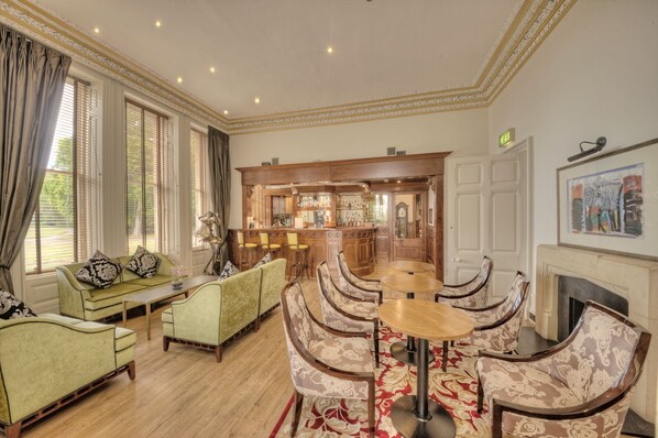 A spacious room with a bar area, seating arrangements, and a fireplace. - Muthu Newton Hotel (Near Inverness Airport) (Nairn)