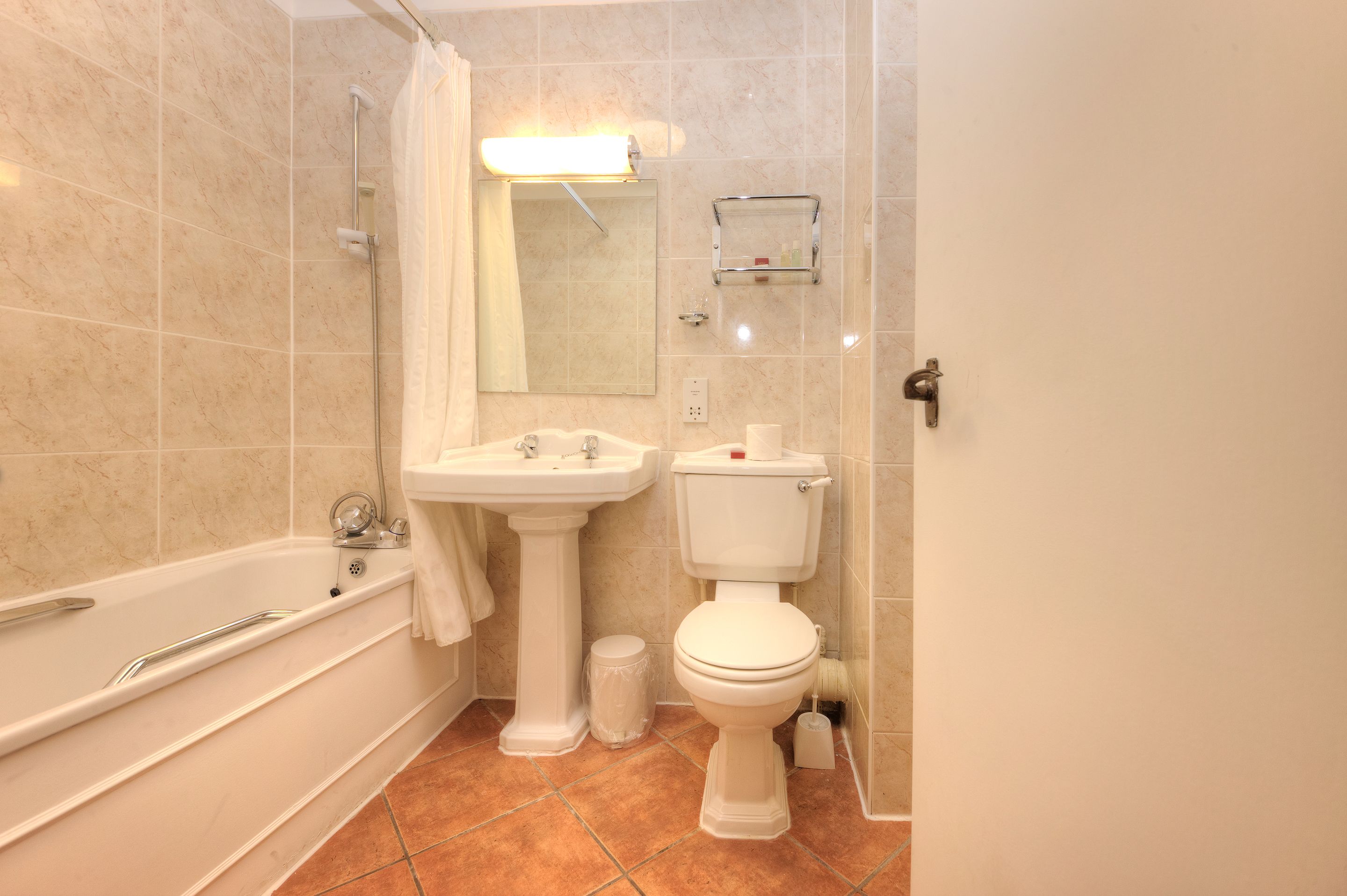 Un baño con bañera, lavamanos, inodoro y cortina de ducha.