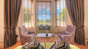 A room with a bay window, two patterned armchairs, a sofa, and a coffee table with books and a vase. - Muthu Newton Hotel (Near Inverness Airport) (Nairn)