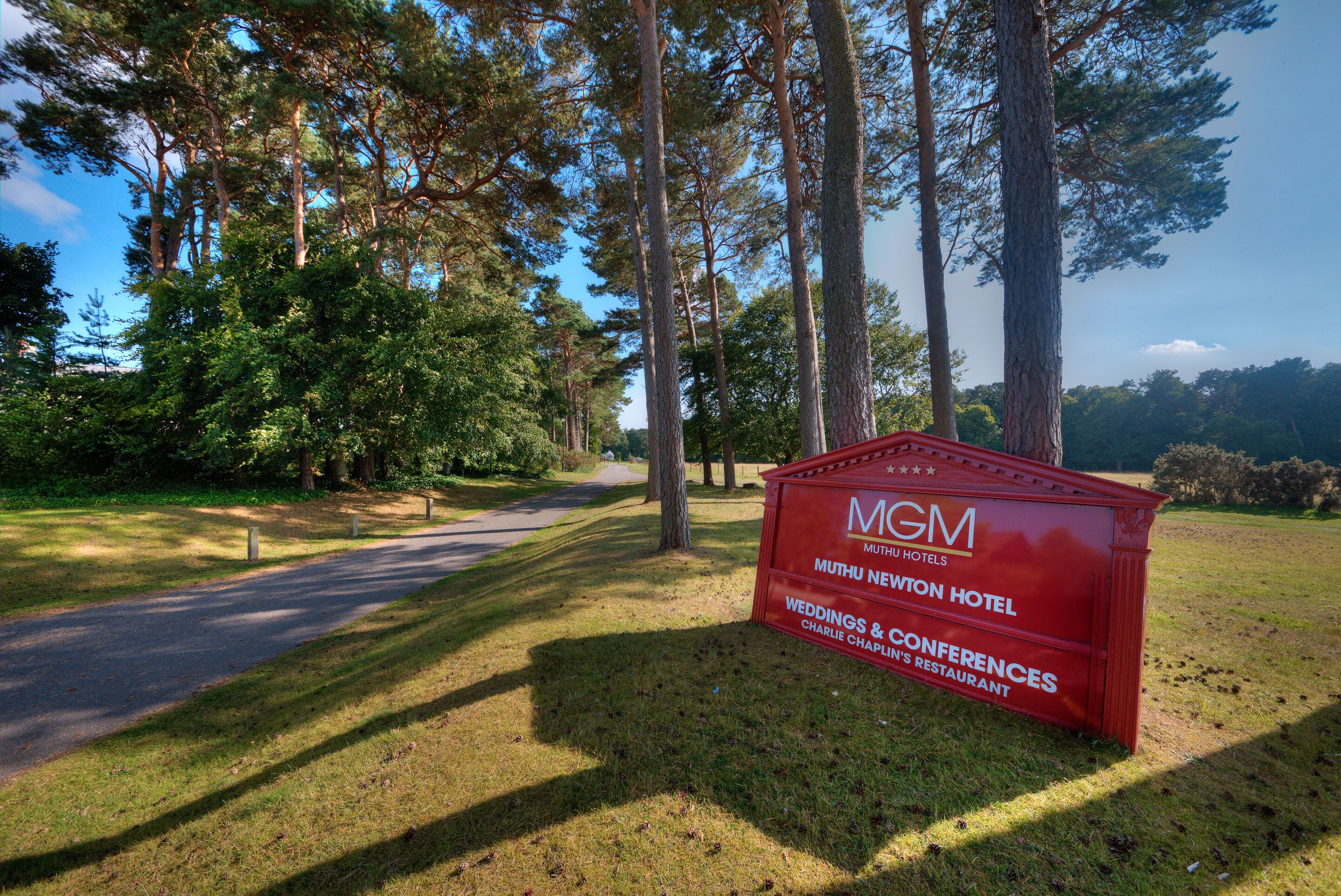Ein rotes Schild für das MGM Muthu Newtown Hotel, das anbietet Hochzeiten, Konferenzen und ein Restaurant.