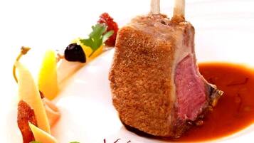Un plato con un chuletón de cordero, rebozado y acompañado de salsa.