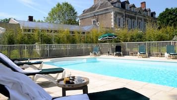 Una piscina al aire libre, sillones reclinables de piscina