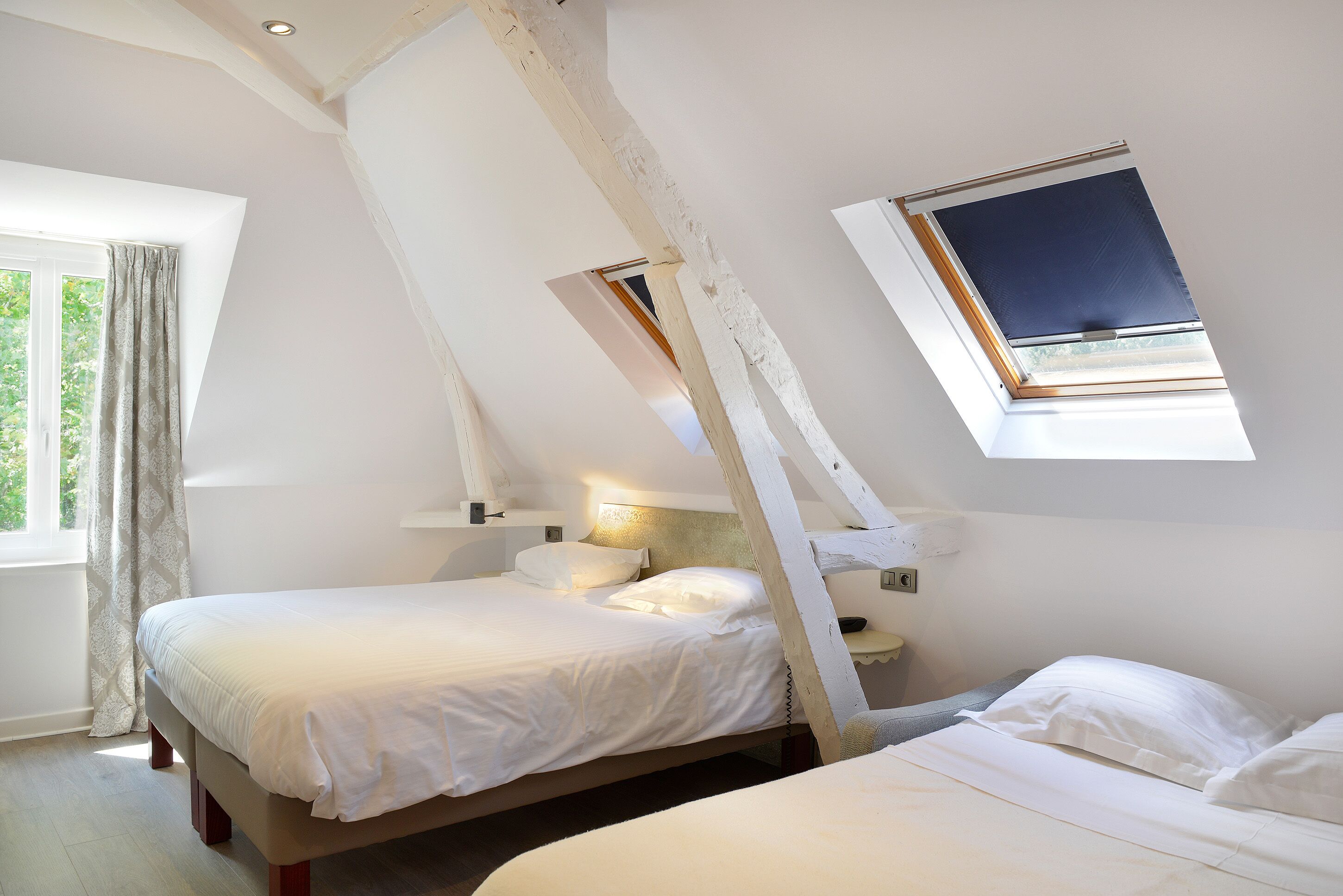 Un dormitorio con dos camas, un tragaluz y una ventana con cortinas.