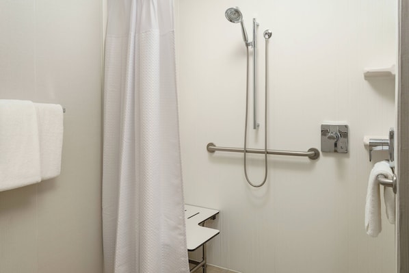 Baño con ducha, barra de apoyo y toallero.