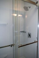 Un box de ducha moderno con puerta de cristal, cabezal de ducha de mano y panel de control.
