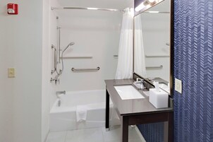 A modern bathroom with a bathtub, a vanity with a mirror, and a shower area.