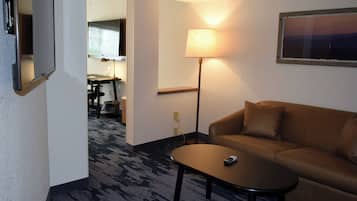 Habitación de hotel con sofá marrón, una mesita, una lámpara y un cuadro en la pared.