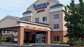Un hotel Fairfield Inn & Suites Marriott con entrada cubierta, varias ventanas y un área ajardinada con rocas y plantas.