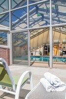 Una piscina techada, una piscina al aire libre, sombrillas