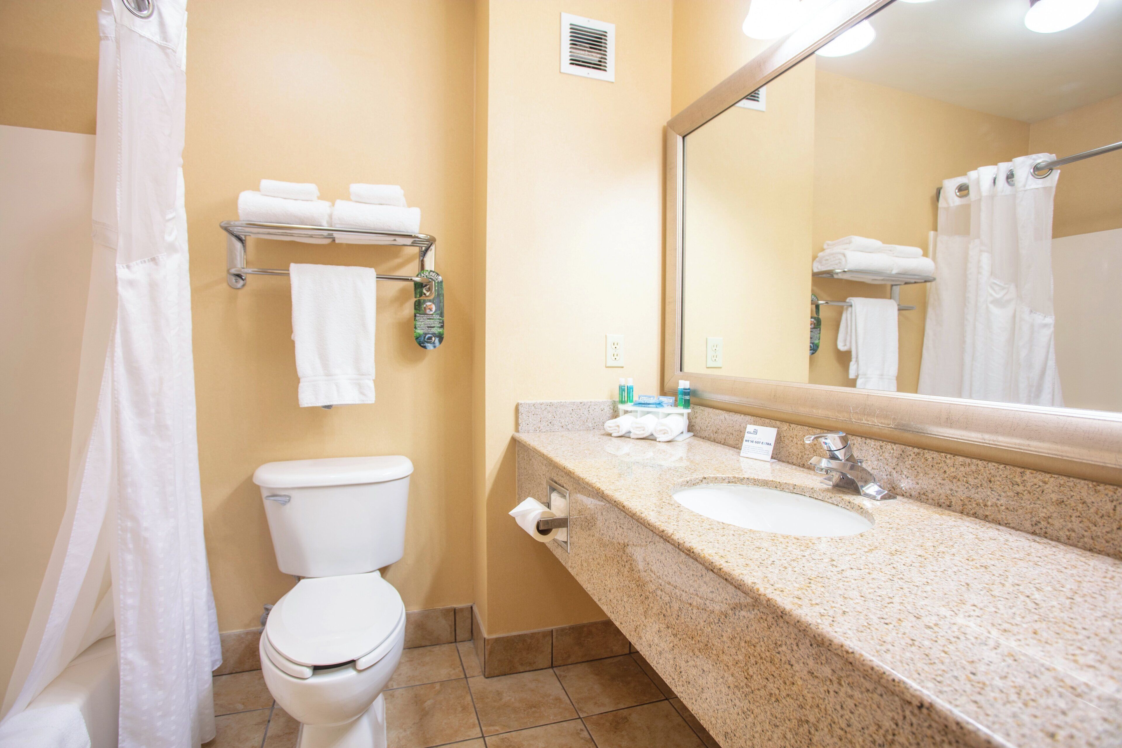 Un baño con inodoro, lavamanos y perchero para toallas.