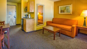 A compact hotel room with a kitchenette, a sofa, a coffee table, and a dining table. - Holiday Inn Express & Suites Richland by IHG (Richland)