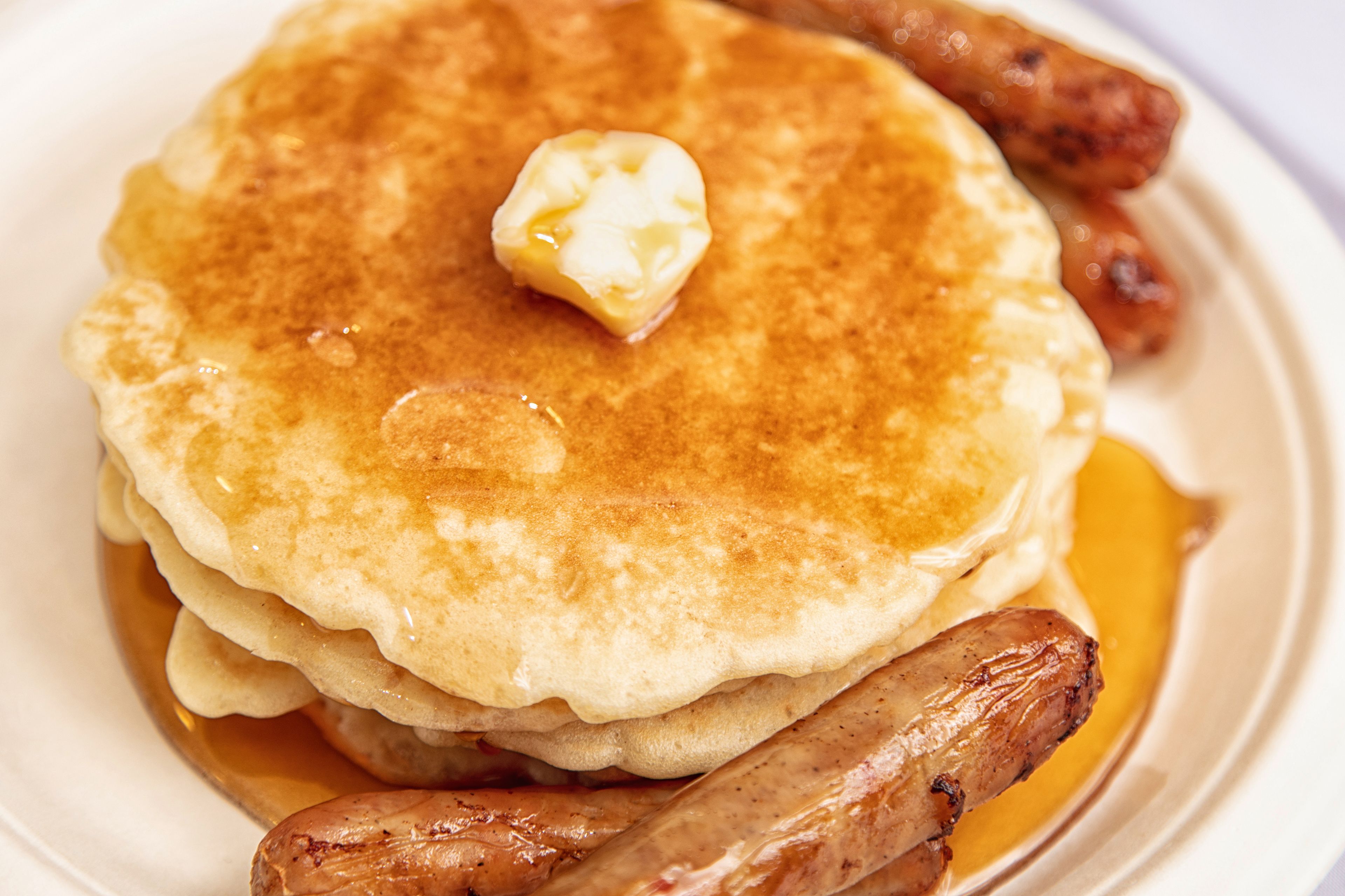 Een stapel pannenkoeken met stroop en een toefje boter.