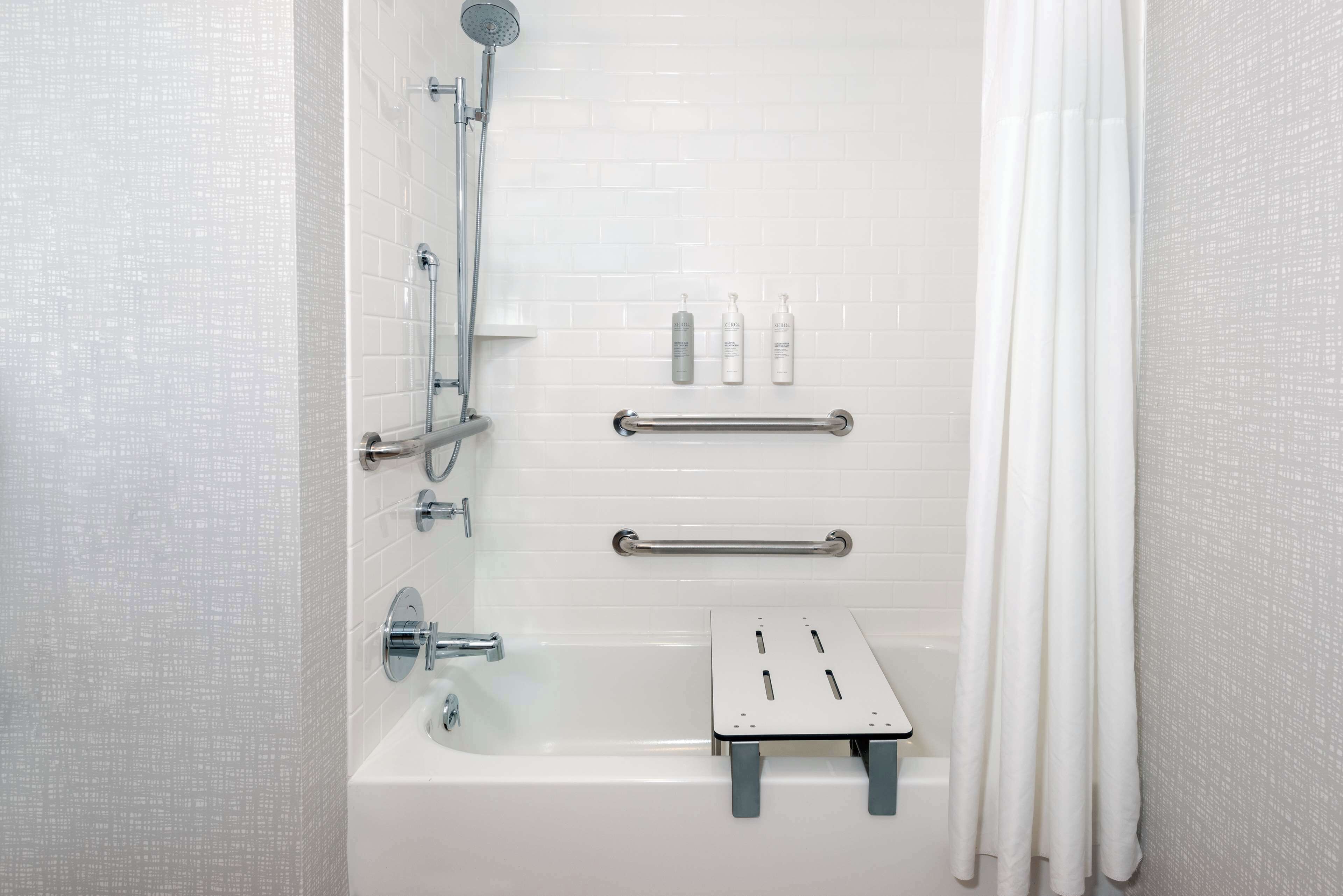Un baño moderno con ducha de vidrio, bañera y un pequeño estante con artículos de aseo.