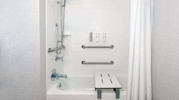 Un baño moderno con ducha de vidrio, bañera y un pequeño estante con artículos de aseo.