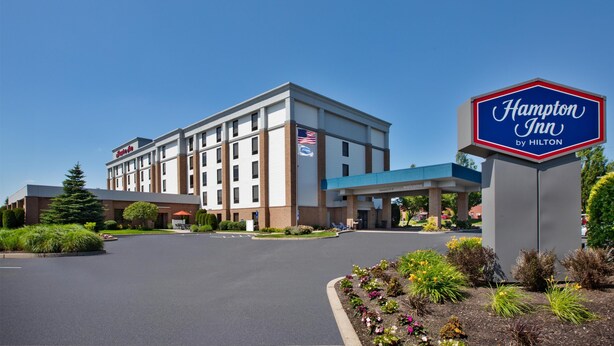 Un hotel Hampton Inn by Hilton con cielo despejado, estacionamiento y jardines ajardinados.