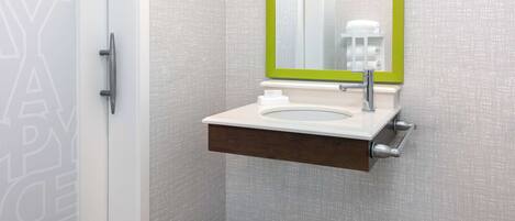 Un baño con lavamanos blanco, espejo con marco verde y un perchero para toallas.