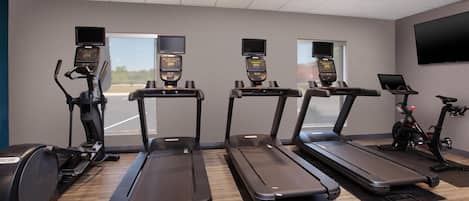 A gym with four treadmills, one elliptical, and a stationary bike.