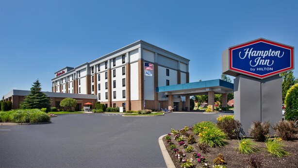 A Hampton Inn by Hilton hotel with a clear sky, a parking lot, and landscaped gardens. - Hampton Inn Coventry - Warwick Area (Coventry)