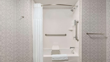 A modern bathroom with a shower, a toilet, and a handrail.