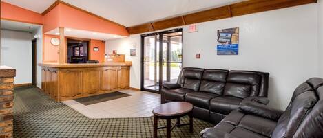 A lobby with a reception desk, a leather sofa, a small table, and a ceiling fan.