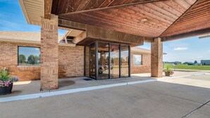 A building with a brick facade, a covered entrance with glass doors, and a clear sky. - Motel 6 Marion, IL (Marion)
