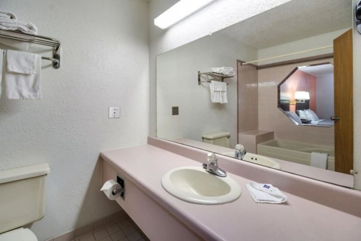 A bathroom with a sink, mirror, and towel rack.