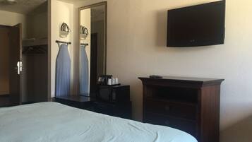 A hotel room with a bed, a dresser, a television, and a mirror.
