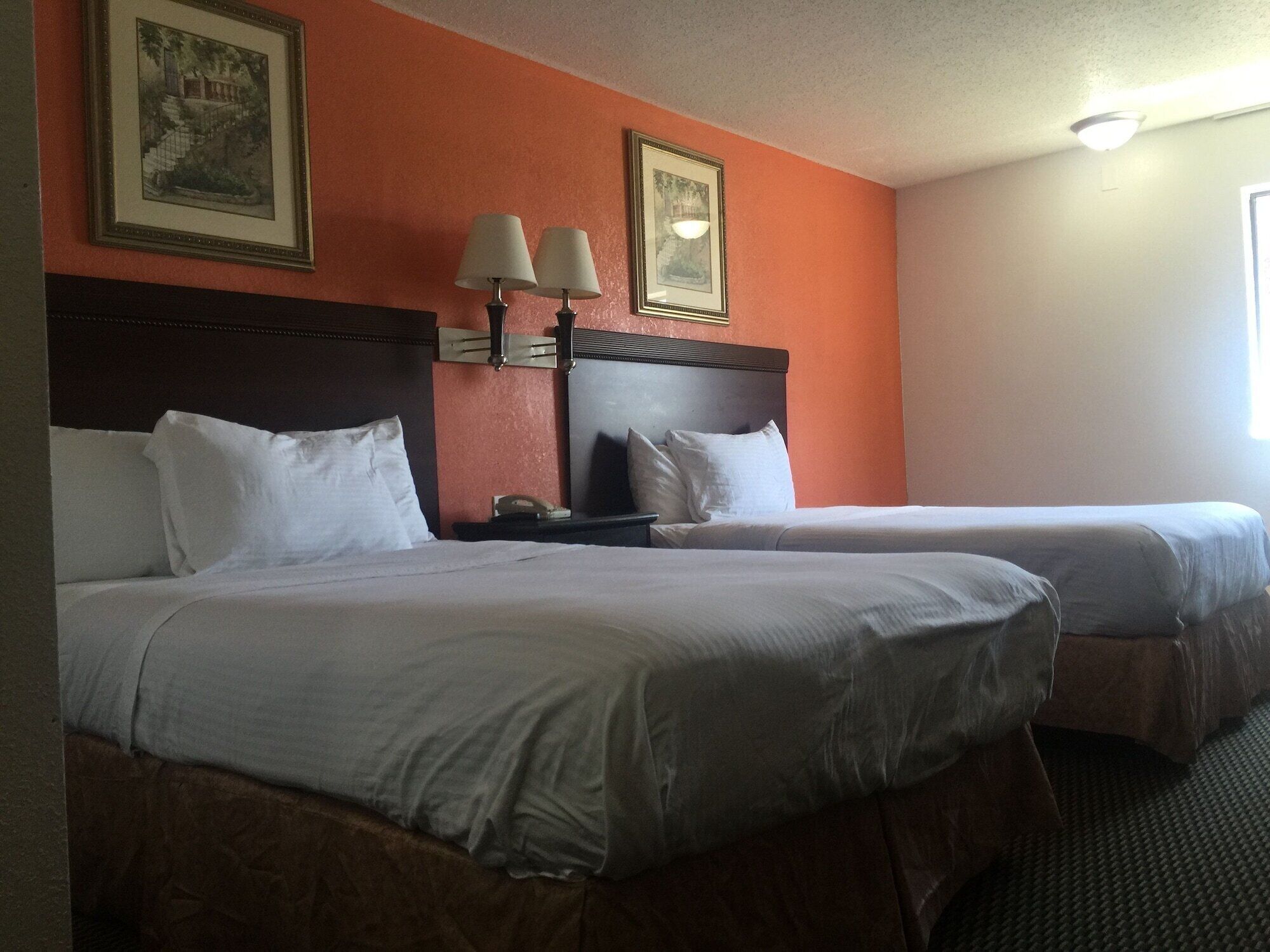 Une chambre d’hôtel avec deux lits, une table de chevet et deux lampes fixées au mur.