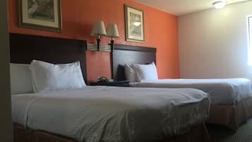 A hotel room with two beds, a nightstand, and two wall-mounted lamps.
