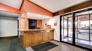A reception area with a wooden counter, a clock, and a door leading outside. - Motel 6 Marion, IL (Marion)