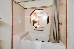 Bathroom features a bathtub and a hexagonal mirror.