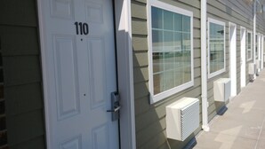 A building with a white door marked with the number 110, air conditioning units, and a row of windows. - Boarders Inn & Suites by Cobblestone Hotels – Broken Bow (Broken Bow)