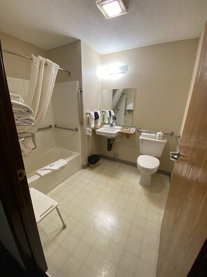 Une salle de bain d’hôtel standard, équipée d’une baignoire, de toilettes, d’un lavabo et d’un miroir.