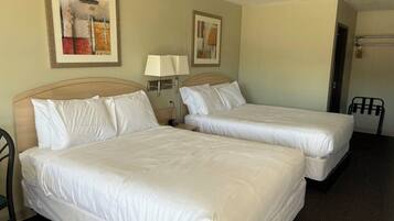 A hotel room with two beds, a nightstand with a lamp, and artwork on the walls.