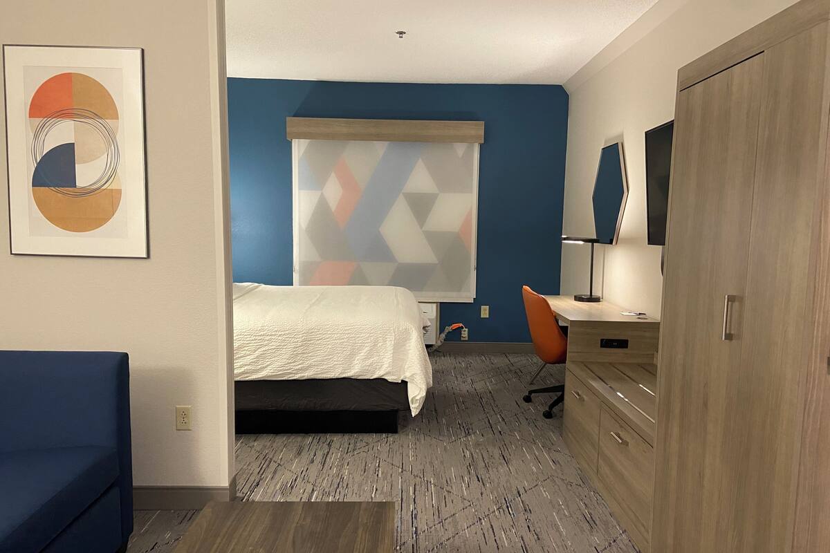 A hotel room with a bed, a desk, a chair, and a wardrobe.