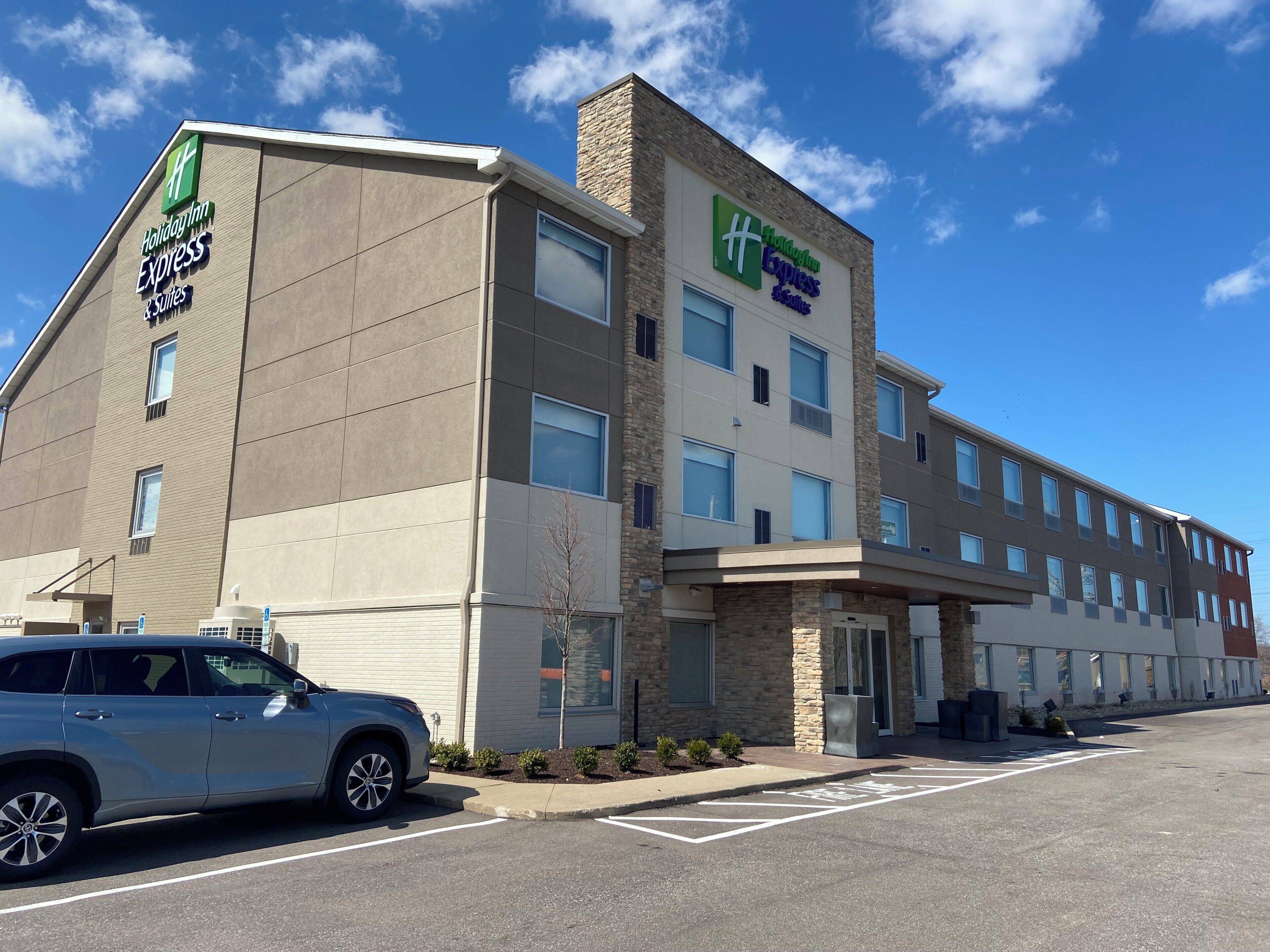 Edificio de Holiday Inn Express con estacionamiento y un automóvil estacionado.