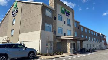 Edificio de Holiday Inn Express con estacionamiento y un automóvil estacionado.