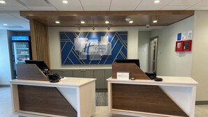 A reception area with two counters, a digital screen, and a wall-mounted sign. - Holiday Inn Express & Suites Elyria by IHG (Elyria)