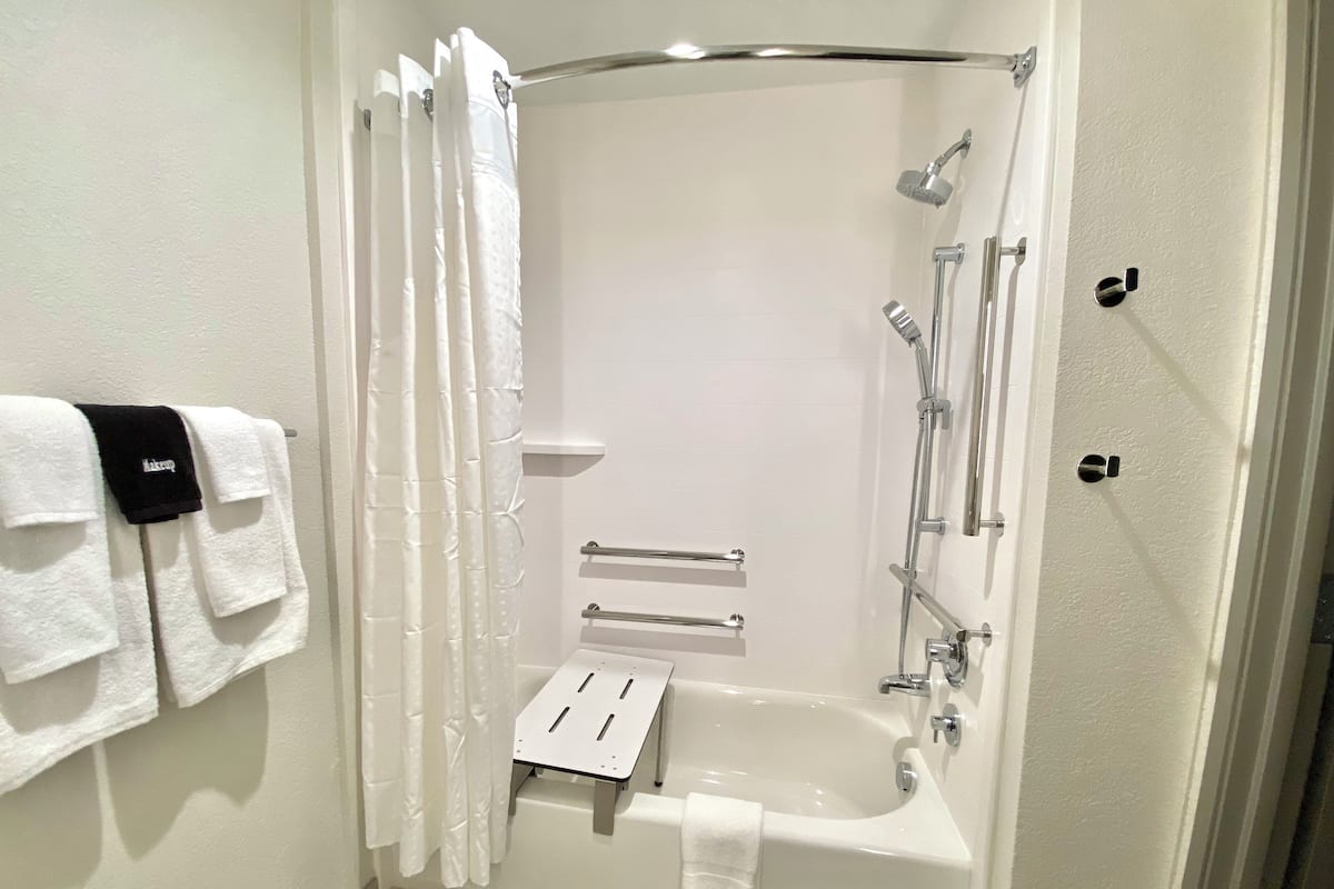 A modern bathroom with a bathtub, shower, and toilet.