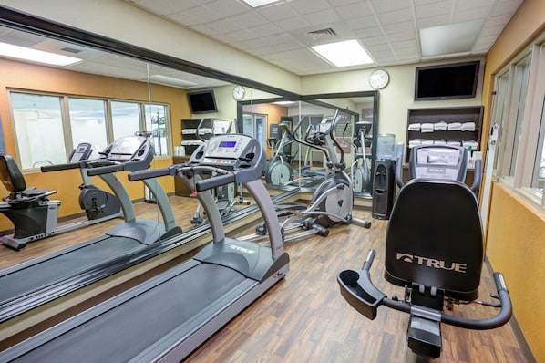 Un gimnasio con cintas de correr, elípticas y máquinas de pesas.