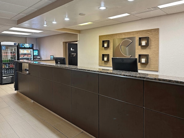 A reception area with a counter, a wall-mounted clock, and a vending machine. - Concord Suites (Concord)