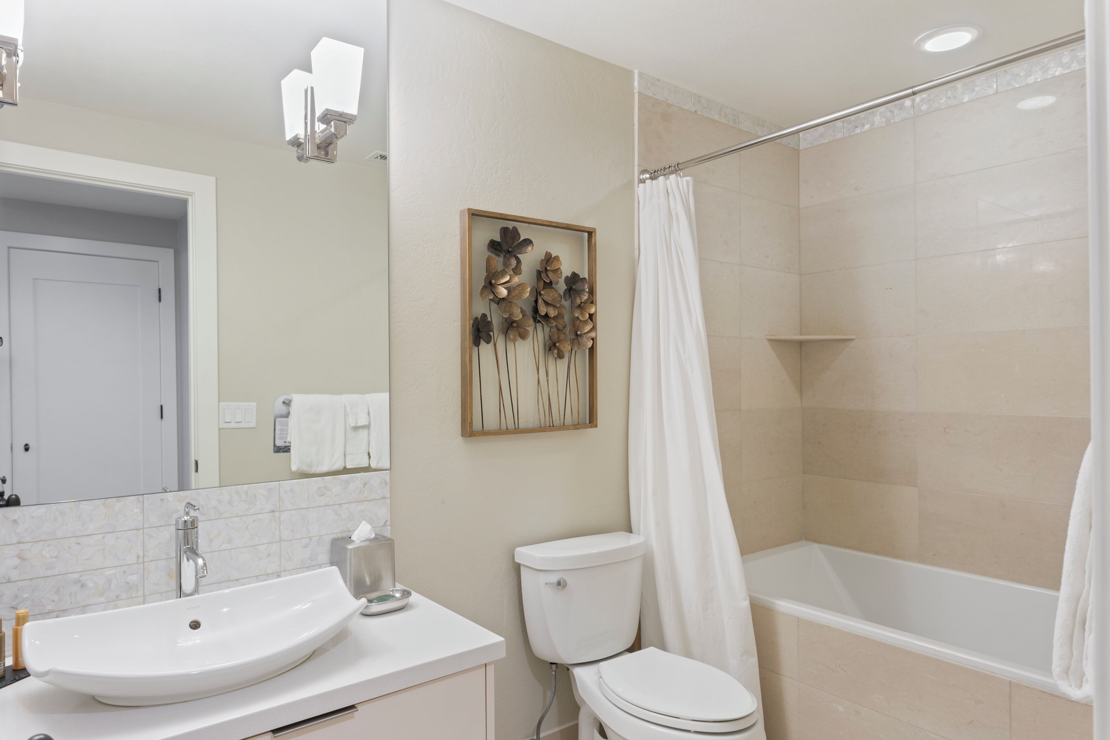 Une salle de bain avec un lavabo, des toilettes et une baignoire, le tout de couleur blanche.