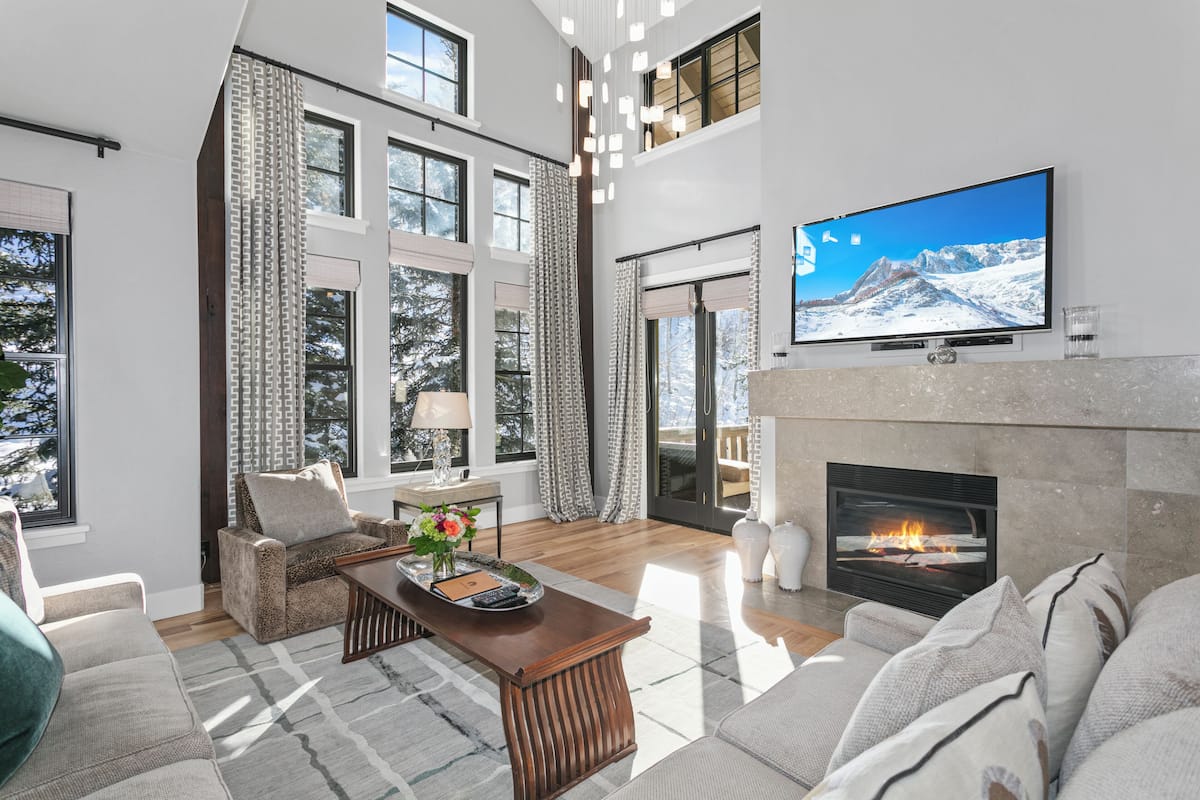 A spacious living room with a fireplace, large windows, and a flat-screen TV.