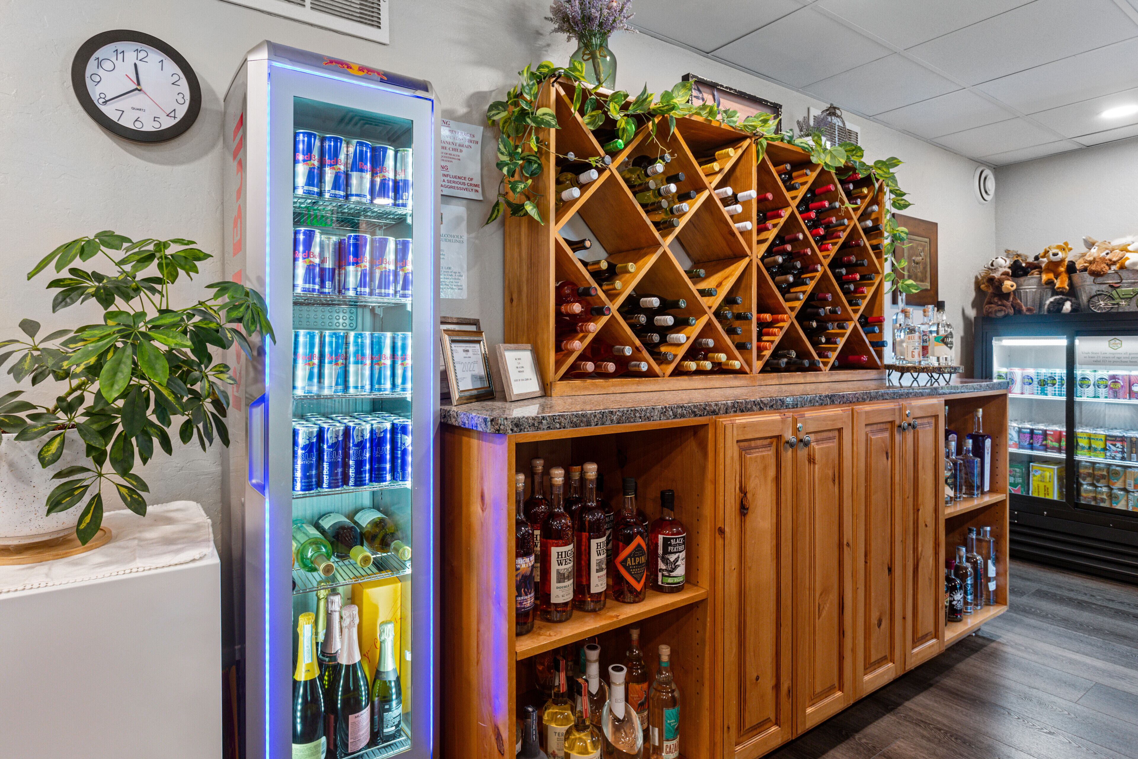Zona de bar con una estantería para vinos, un dispensador de bebidas refrigerado y estantes con botellas.