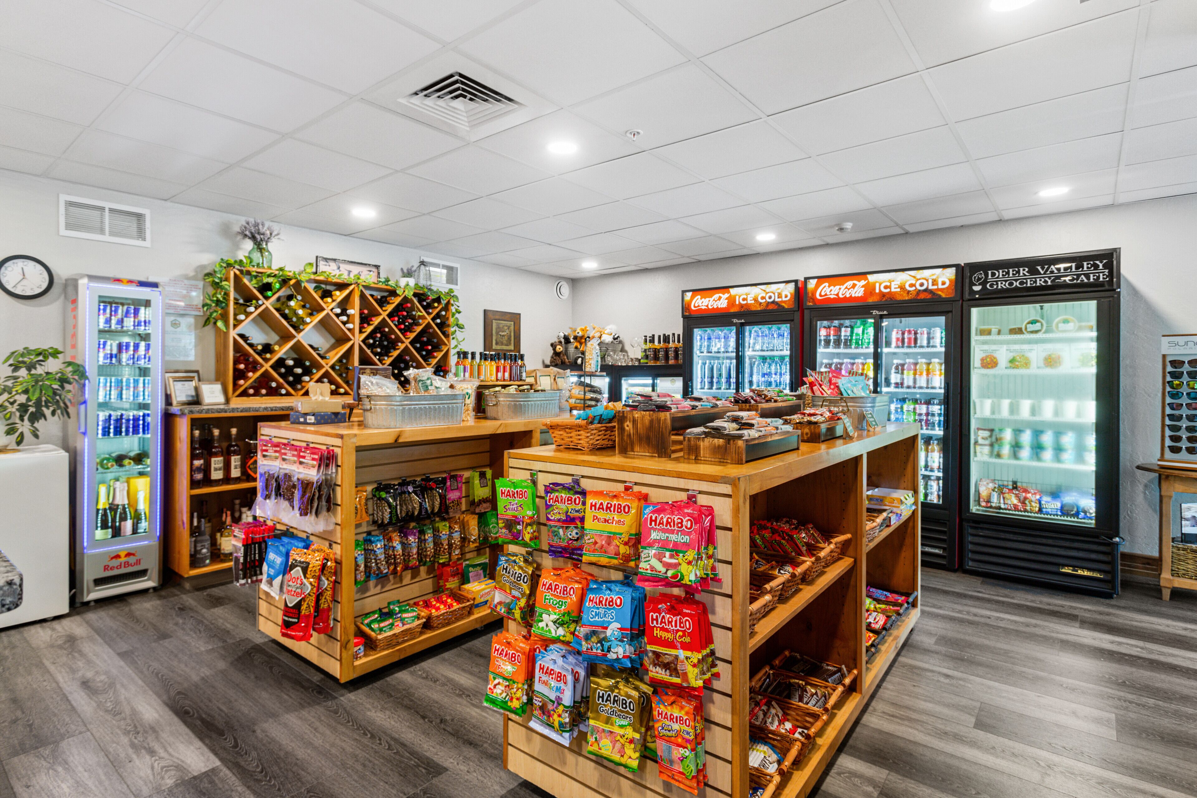 A grocery store interior with refrigerated sections, snack displays, and a clock on the wall.