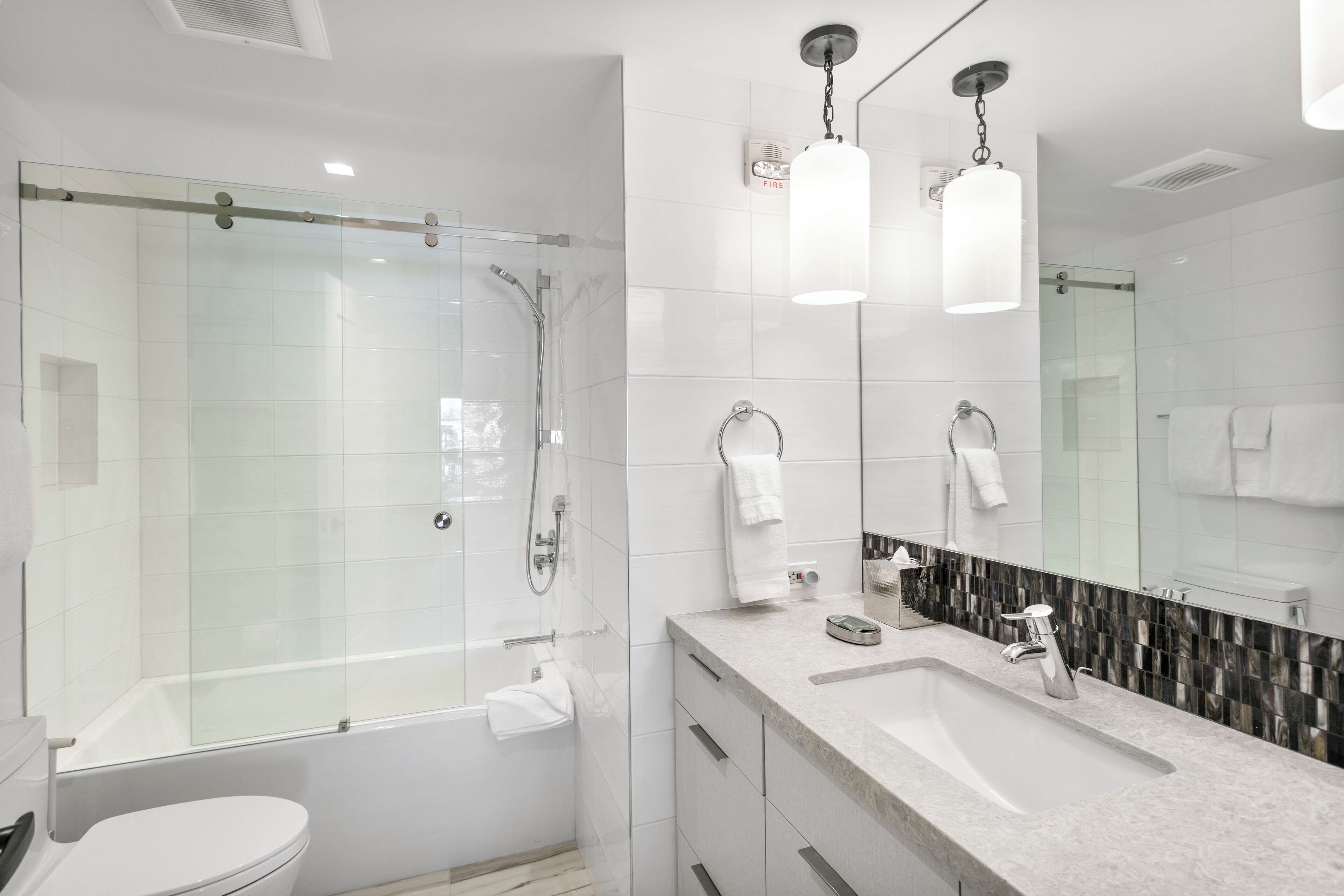 A modern bathroom with a glass-enclosed shower, a large sink, and a vanity with drawers.