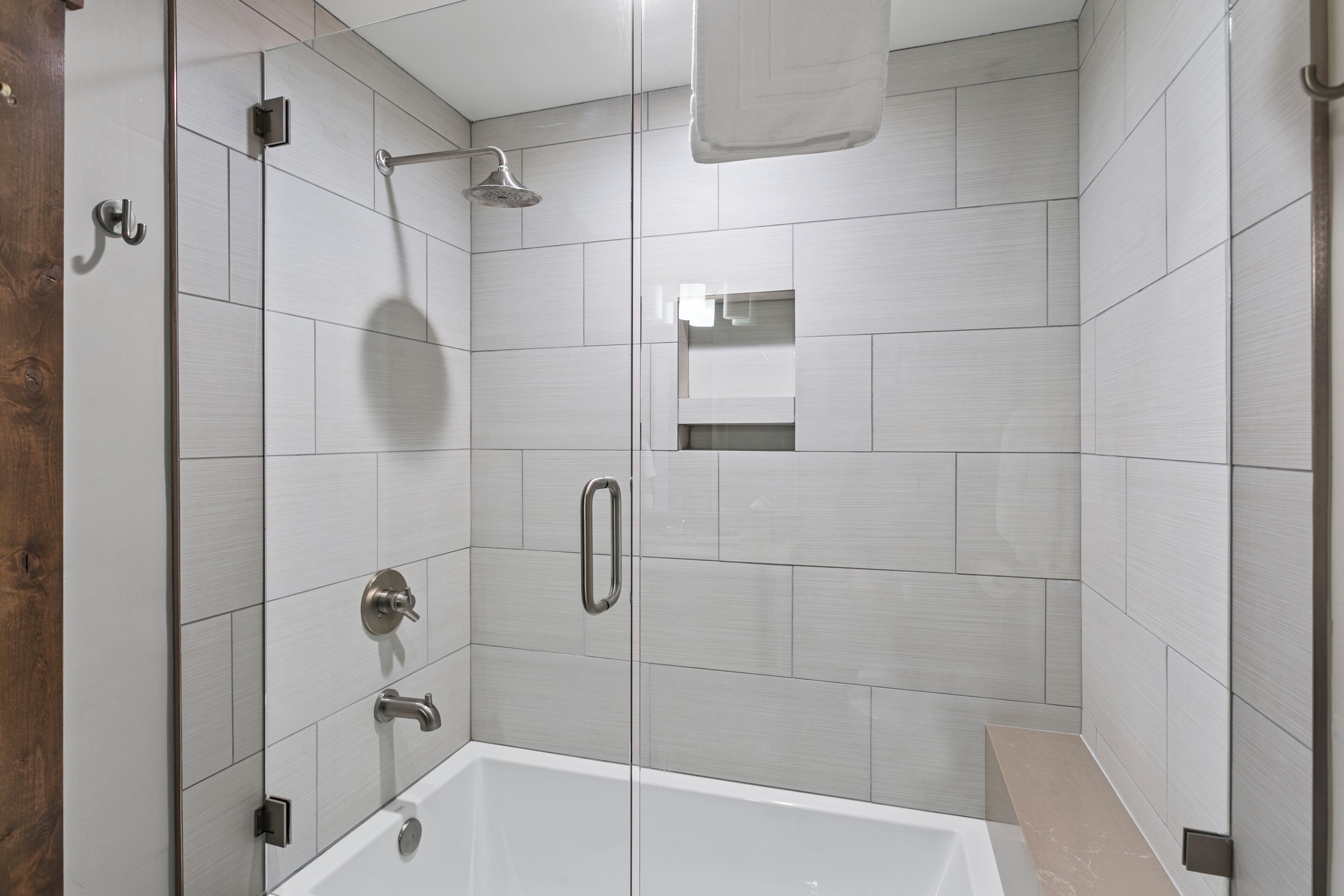 Un baño moderno con ducha envuelta en vidrio, una bañera y un tocador con espejo.